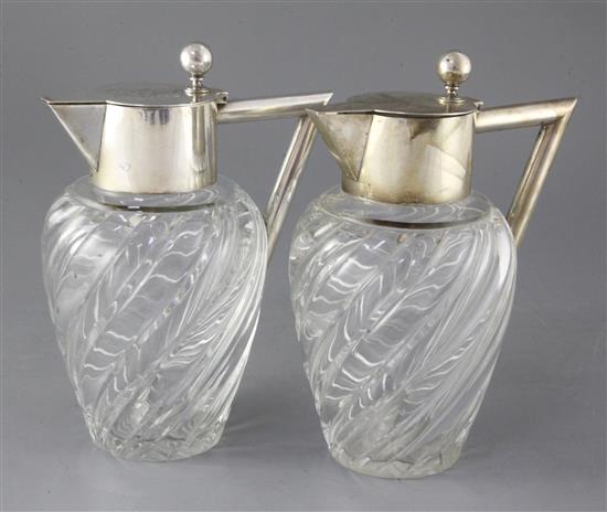 A stylish pair of early 20th century German 800 standard silver mounted wrythened glass claret jugs, 22.5cm.